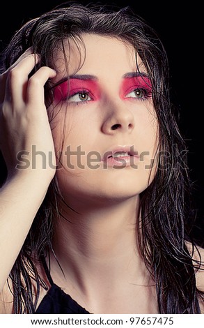 Woman with fancy make up and her hair wet fashionably posing in the studio on black background
