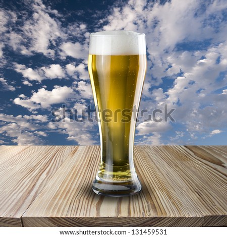 Glass of Beer on wood table with clear sky background