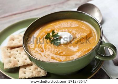 Pumpkin soup with crackers.  Served in green soup bowl.