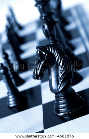 Black knight on a chessboard, in blue duotone.  Shallow depth of field.