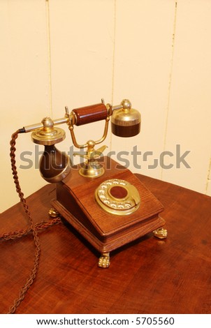 Vintage dial telephone, made from rich timber and brass, resting on antique telephone table.