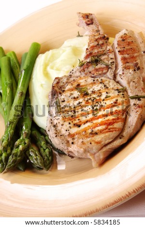 Grilled pork chop with potato mash and fresh asparagus.