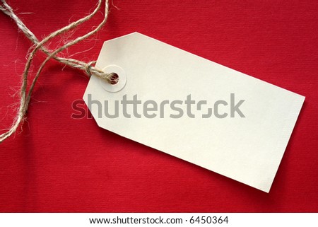 Blank tag tied with string, on vibrant red textured background.