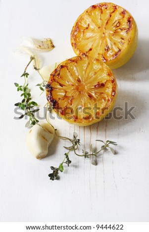 Roasted lemon, garlic and thyme on weathered white timber.  Perfect taste combination of flavours.