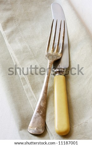 Vintage knife and fork on linen napkin.  Bone-handled knife and tarnished silver fork.