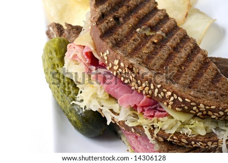 Reuben sandwich on rye bread, with corned beef, sauerkraut and Swiss cheese.  Served with a pickle and potato chips on the side.