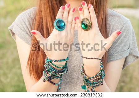portrait of beautiful young brunette woman posing in rings and multiple bracelets