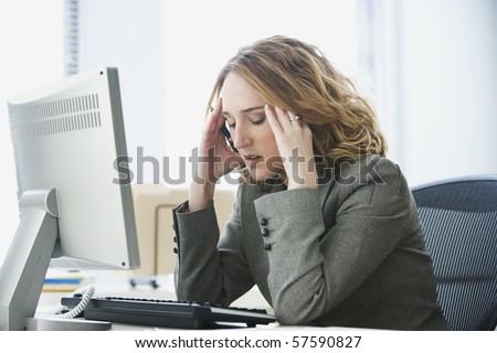 A young businesswoman is looking stressed as she works at her computer. Horizontal shot.