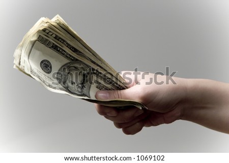 A person's hand offering a stack of US twenty dollar bills