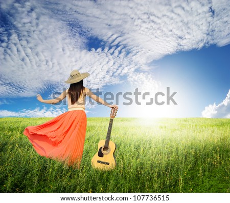 Woman and guitar standing on meadow with Cloud sky