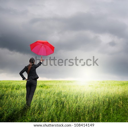 Business umbrella woman standing to rainclouds in grassland with red umbrella