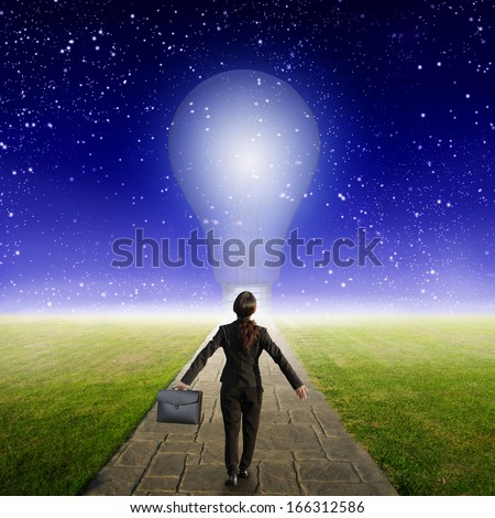 Relax business woman holding bag on Concrete road to Big idea bulb in Grass fields and star night
