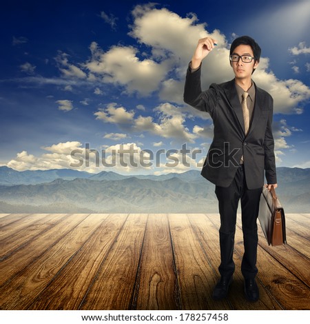 Business man writing  and standing   on Wood floor and blue sky mountain