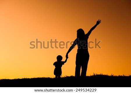 silhouette of a mother and son playing outdoors at sunset