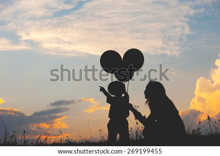 Silhouette of A mother and son playing outdoors at sunset