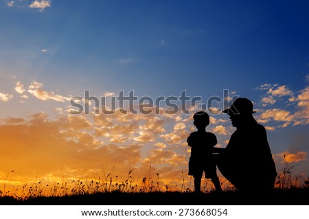 Silhouette of a mother and son playing outdoors at sunset silhouette