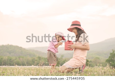 Happy family Vintage tone. A mother and son giving gift box on outdoors. Copy space