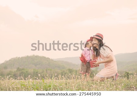 Happy family Vintage tone. A mother and son giving gift box on outdoors. Copy space