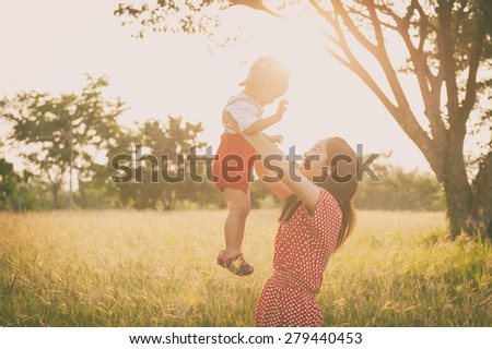 happy family. A mother and son playing in grass fields outdoors at evening.Vintage Tone and copy space