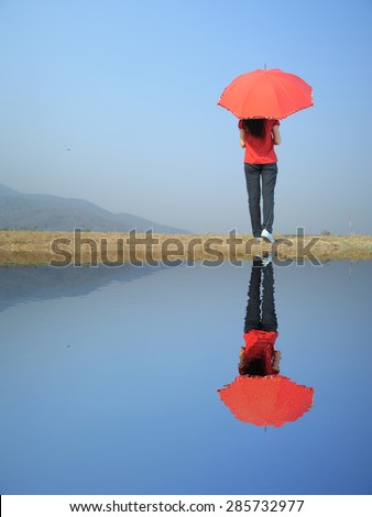 Water Reflection Red umbrella woman and blue sky.Copy space