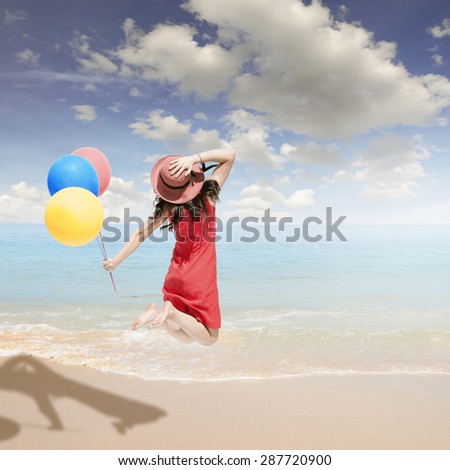 Happy Woman jumping and holding balloons on the beach and clouds  sky.Summer holiday concept.