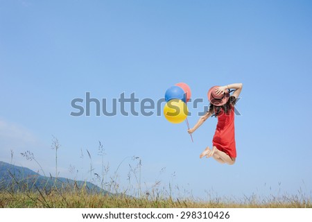 Happy Woman Jumping and holding balloon with blue sky outdoor.Summer Vacation concept
