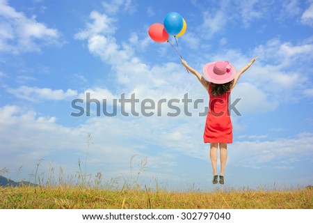 Happy Woman Jumping and holding balloon with blue sky outdoor.Summer Vacation concept