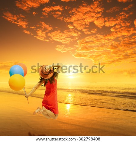 Happy Woman Jumping and holding balloons on Beach Sunset.Summer holiday concept.