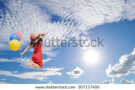Happy Woman jumping and holding balloons  to blue cloud sky. Vacation summer concept