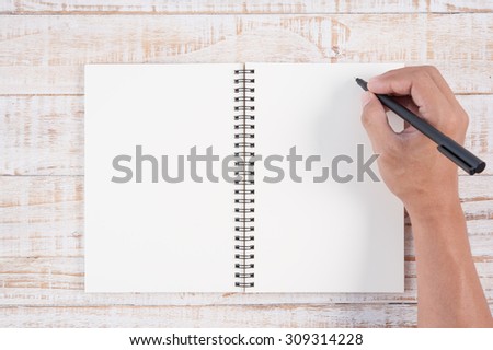 Man hand holding pen and writing notebook  on wood table for text and background.copy space