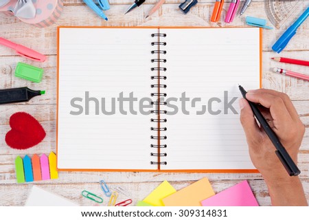 Man hand writing  Notebook paper and school or office tools on vintage wood table for text and background.copy space