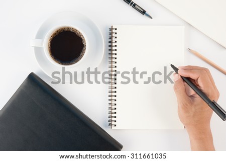 Cup of hot coffee and man hand writing notebook on  white background .copy space
