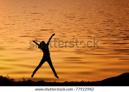 Happy woman jump and sunset silhouette in Lake