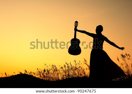 Woman and guitar with  sunset silhouette