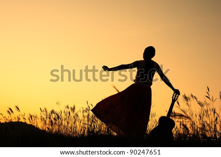 Woman and guitar with sunset silhouette