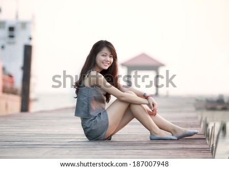 beautiful asian woman sitting on wood pier with relaxing emotion and smiling to camera use for attractive woman and people female topic