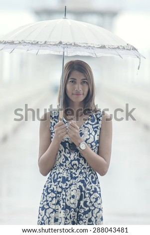 portrait of beautiful tan skin woman with umbrella standing among raining day