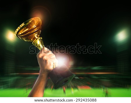 hand rising soccer football championship cup on sport competiton in stadium background