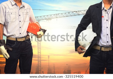 two engineer man working with white safety helmet against crane and  building construction site use for civil engineering and construction industrial business