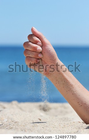 Hand throws sand on the seashore