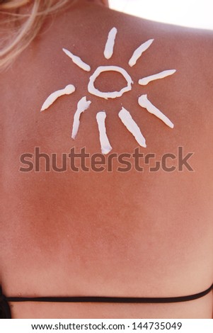 sun cream on the female back on the beach
