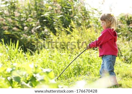 a beautiful little girl in nature playing with a stick