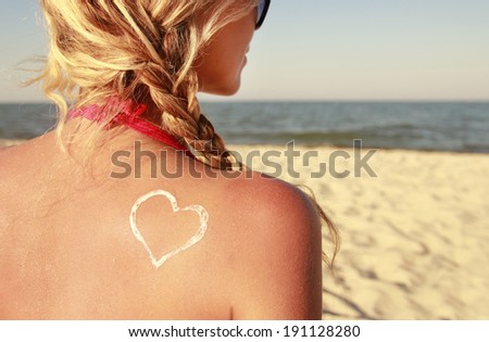 a heart of the cream on the female back on the beach