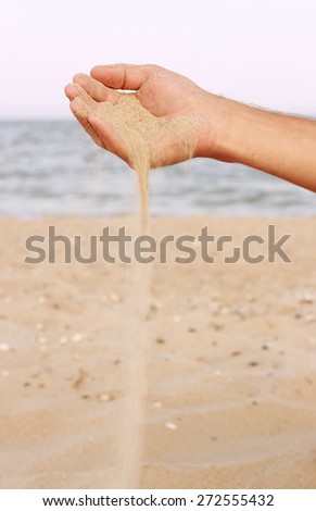 a hand pours sand
