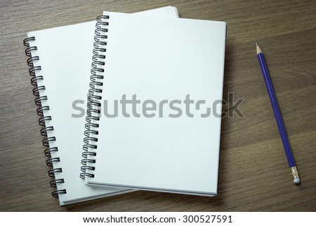 blank spiral notebook and pencil on dark wood background