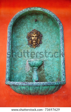 A head water fountain on red wall