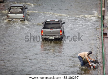 BANGKOK, THAILAND - NOVEMBER 5 : motorcycle accident of a man on flood hits Central of Thailand, higher water levels expected, cars navigating through the flood on November 5,2011 Bangkok, Thailand.