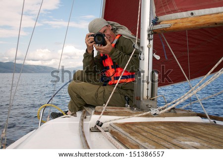 The smiling man photographs, sitting on a yacht nose