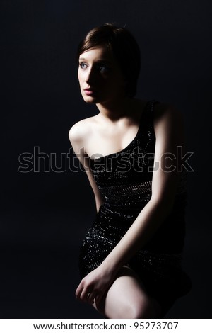 Beautiful woman in sexy evening dress against dark background.