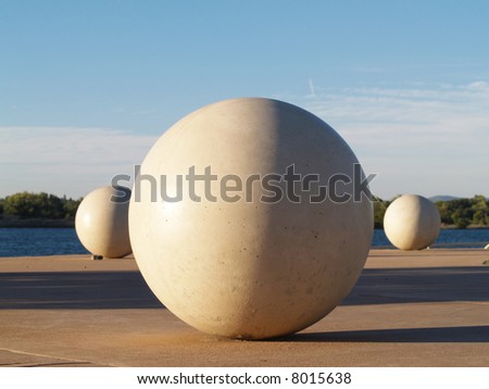 Three white concrete spheres in a park with side lighting